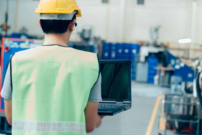industrial engineer with hard hat working with laptop at factory